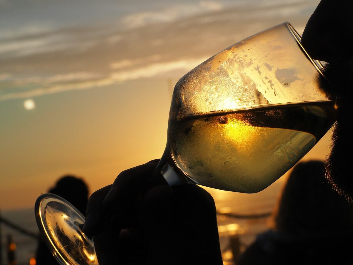 una persona che beve un vino bianco made in italy al tramonto