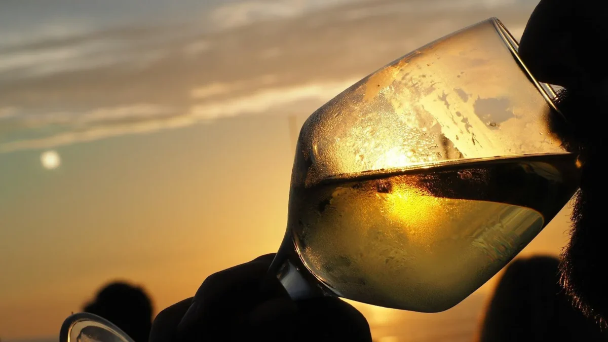 una persona che beve un vino bianco made in italy al tramonto