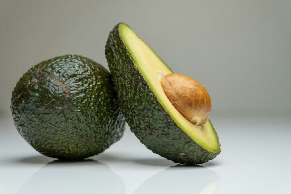 Una coppia di avocadi (frutto), di cui uno tagliato a metà